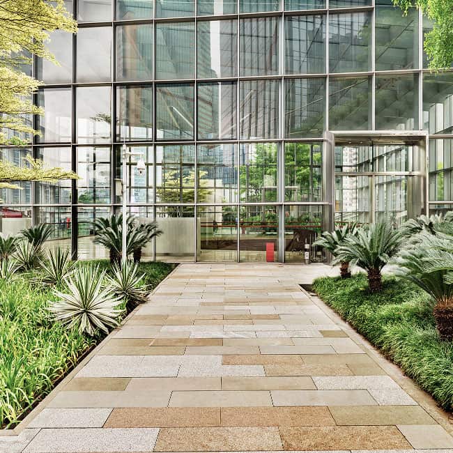 Beautiful landscaped entrance with lush plants and clean pathways for office buildings.
